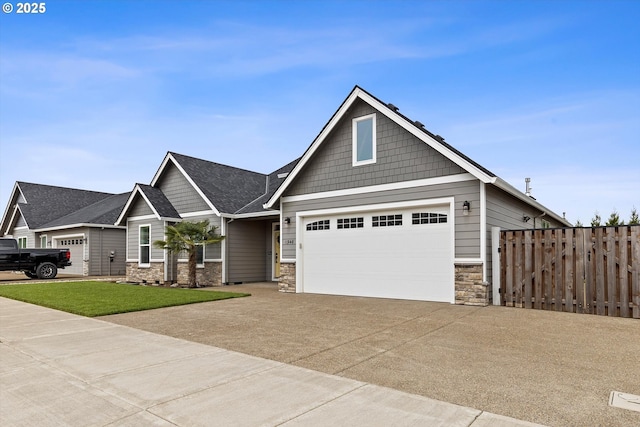 craftsman-style home with a garage, fence, driveway, and stone siding
