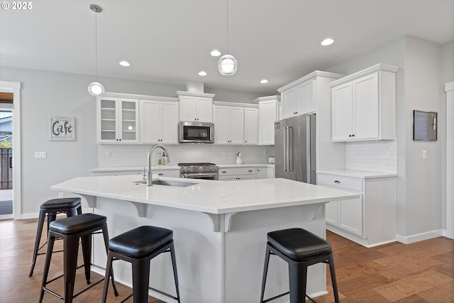 kitchen with tasteful backsplash, a sink, white cabinets, premium appliances, and recessed lighting