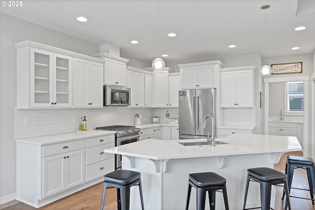 kitchen featuring white cabinets, high end appliances, a sink, and light wood finished floors