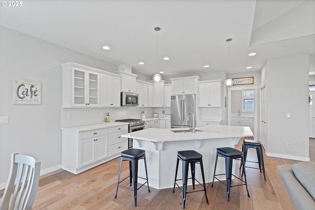 kitchen with a sink, high end appliances, a breakfast bar area, and white cabinetry
