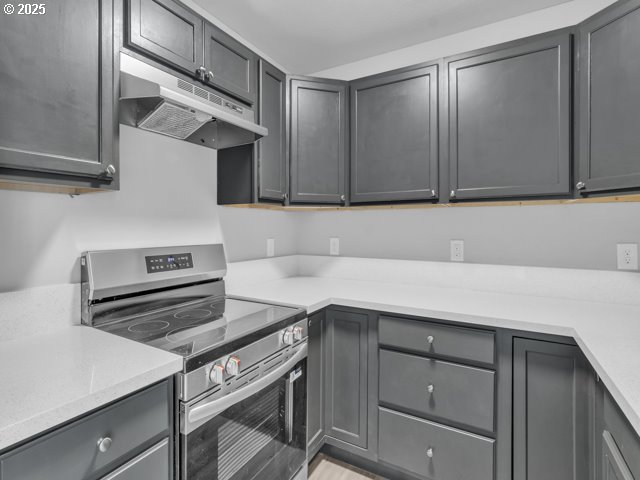 9257 SE Clinton St, Portland, OR 97266 - kitchen featuring stainless steel range with electric cooktop, under cabinet range hood, light countertops, and gray cabinetry