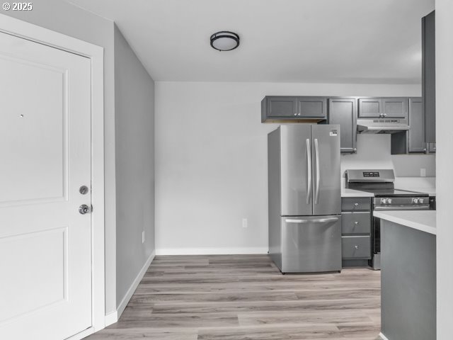 9257 SE Clinton St, Portland, OR 97266 - kitchen featuring stainless steel appliances, gray cabinets, light wood-style floors, under cabinet range hood, and baseboards