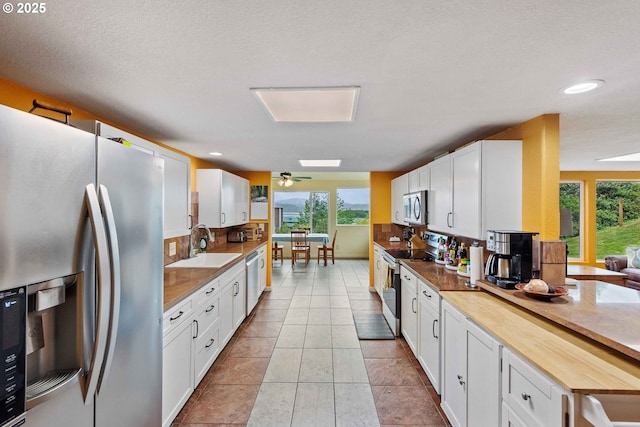 500 State St, North Bend, OR 97459 - kitchen with stainless steel appliances, a sink, white cabinets, tasteful backsplash, and light tile patterned flooring