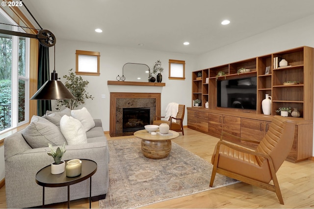 living room with light hardwood / wood-style floors, a tile fireplace, and plenty of natural light