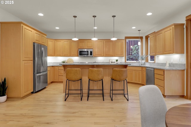 kitchen featuring light stone countertops, a kitchen island, pendant lighting, and appliances with stainless steel finishes