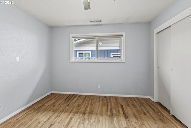 unfurnished bedroom featuring light wood-style floors, a closet, visible vents, and baseboards