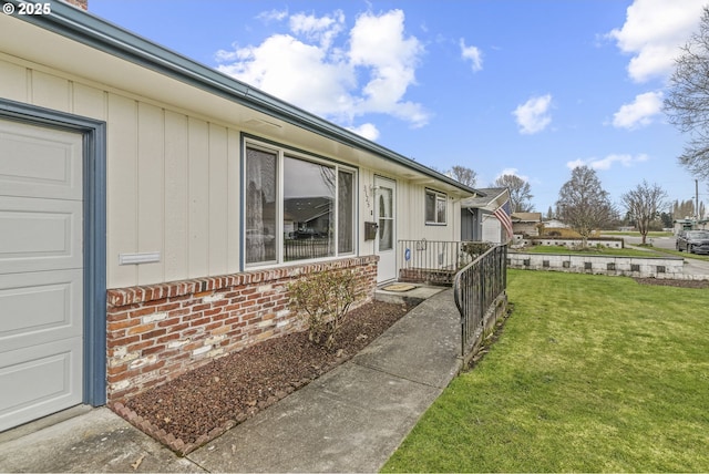 view of side of property featuring a garage, brick siding, and a lawn