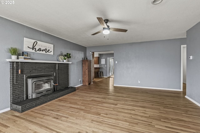 living area featuring ceiling fan, a textured ceiling, baseboards, and wood finished floors