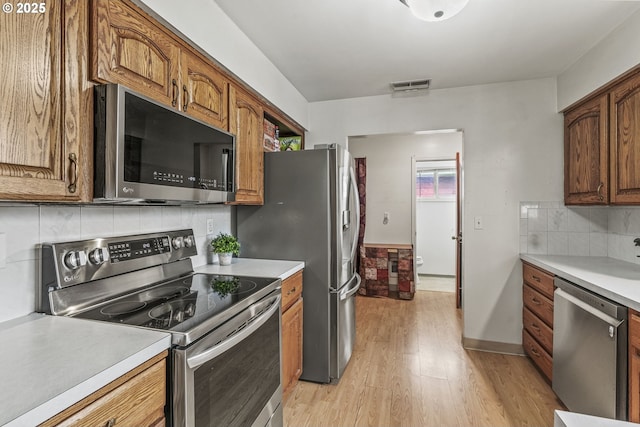 kitchen with visible vents, brown cabinetry, light wood-style flooring, appliances with stainless steel finishes, and light countertops