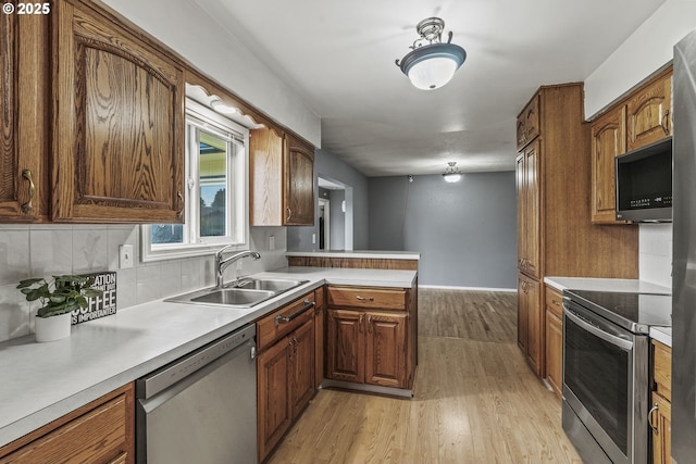 kitchen with a peninsula, stainless steel appliances, a sink, and light countertops