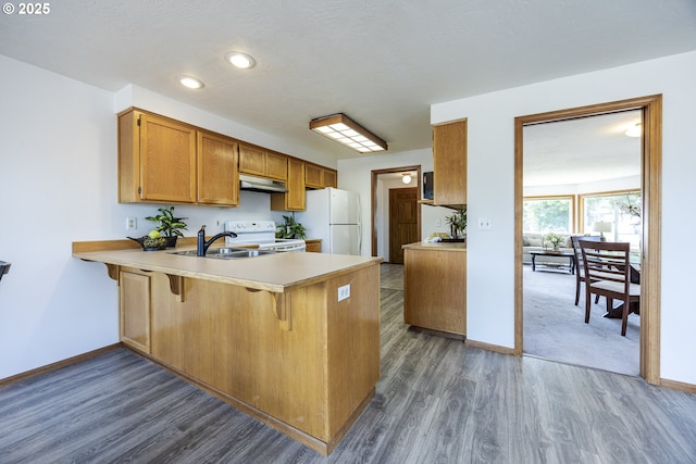 7324 B St, Springfield, OR 97478 - kitchen with white appliances, a peninsula, dark wood-type flooring, light countertops, and under cabinet range hood
