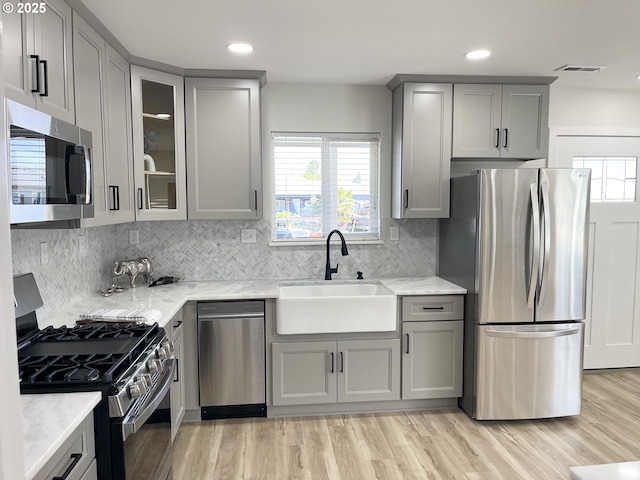 2660 Evergreen Ct, Salem, OR 97301 - kitchen featuring appliances with stainless steel finishes, gray cabinetry, a sink, light stone counters, and light wood-type flooring