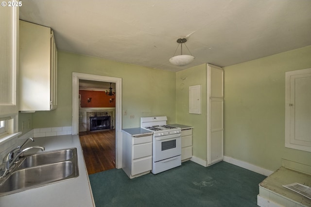 3955 SE Kelly St, Portland, OR 97202 - kitchen featuring white range with gas stovetop, a brick fireplace, white cabinets, and light countertops
