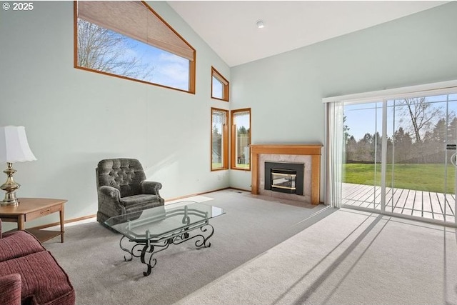 carpeted living room featuring high vaulted ceiling, a tile fireplace, and baseboards