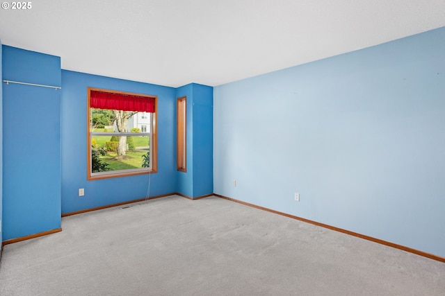 spare room featuring carpet, visible vents, and baseboards