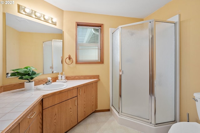 full bathroom featuring a stall shower, baseboards, vanity, and toilet