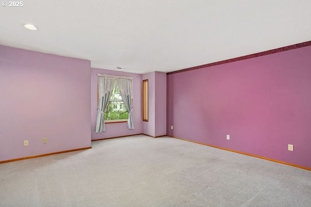 spare room featuring baseboards and light colored carpet