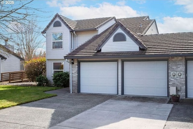 view of front of home featuring a garage, concrete driveway, brick siding, and a tiled roof