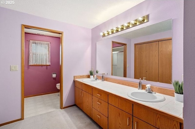 full bathroom with double vanity, baseboards, toilet, and a sink