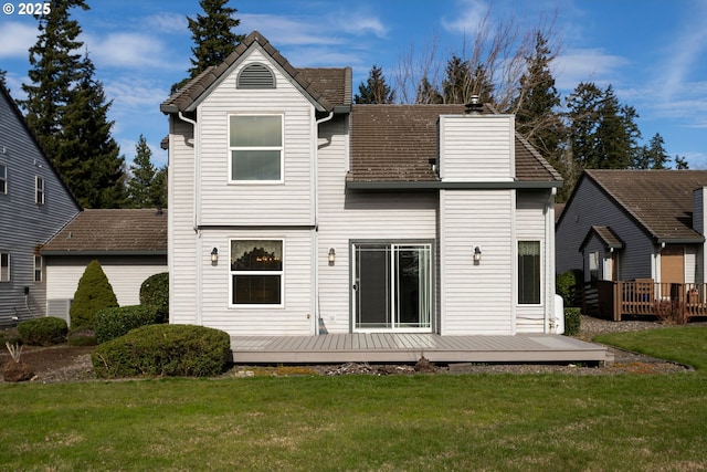 back of property with a chimney, a yard, and a deck