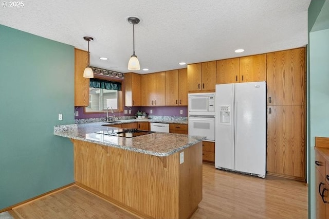 kitchen with white appliances, a peninsula, light stone countertops, light wood-style floors, and pendant lighting