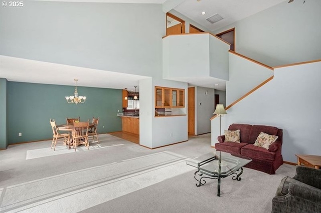 living room with visible vents, an inviting chandelier, light carpet, high vaulted ceiling, and baseboards