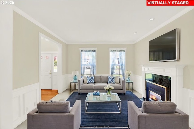 living area featuring a decorative wall, wainscoting, ornamental molding, and a high end fireplace