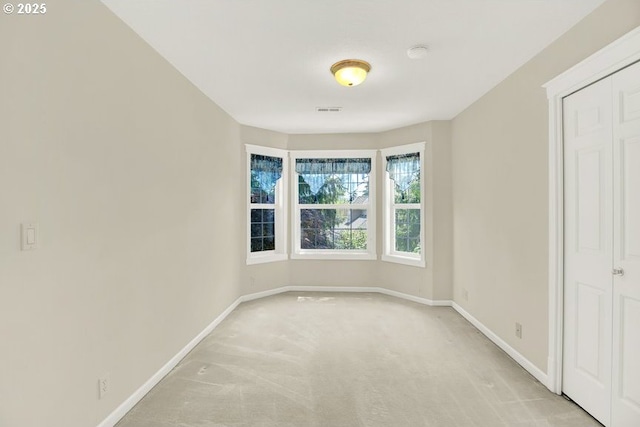 spare room with light colored carpet and baseboards