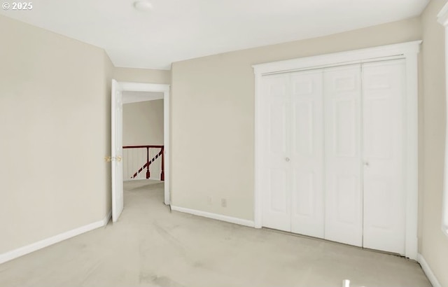 unfurnished bedroom with baseboards, light colored carpet, and a closet