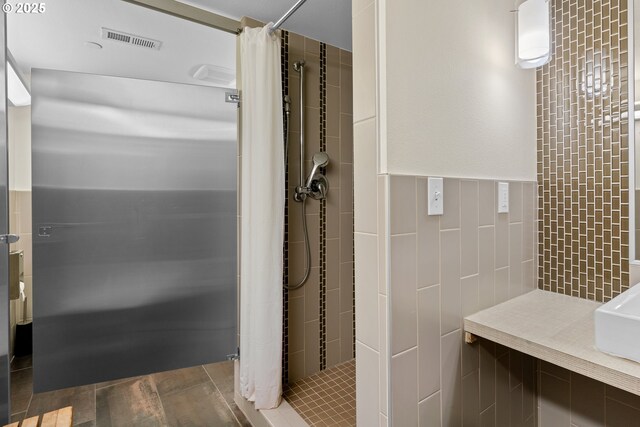 bathroom with a shower with curtain and tile walls