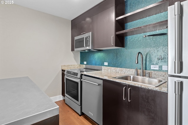 kitchen featuring sink, dark brown cabinets, light hardwood / wood-style flooring, stainless steel appliances, and decorative backsplash