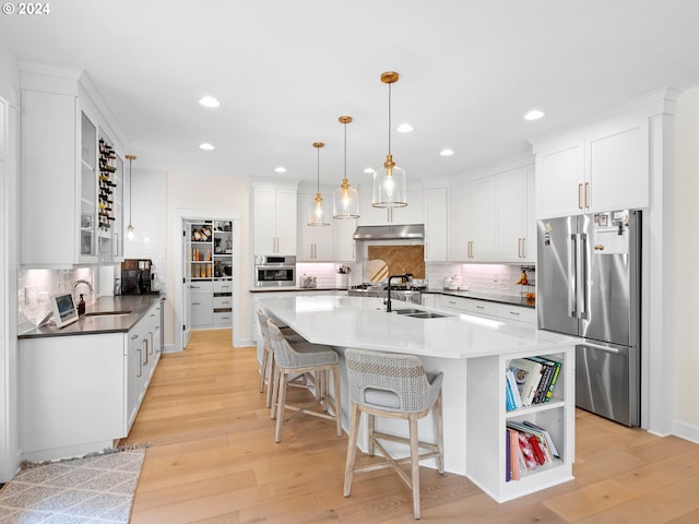 9010 SW Inez St, Tigard, OR 97224 - kitchen with appliances with stainless steel finishes, a sink, under cabinet range hood, backsplash, and light wood-type flooring