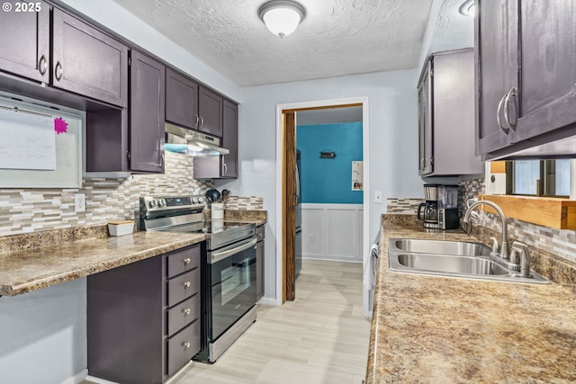 kitchen with sink, a textured ceiling, dark brown cabinets, appliances with stainless steel finishes, and backsplash