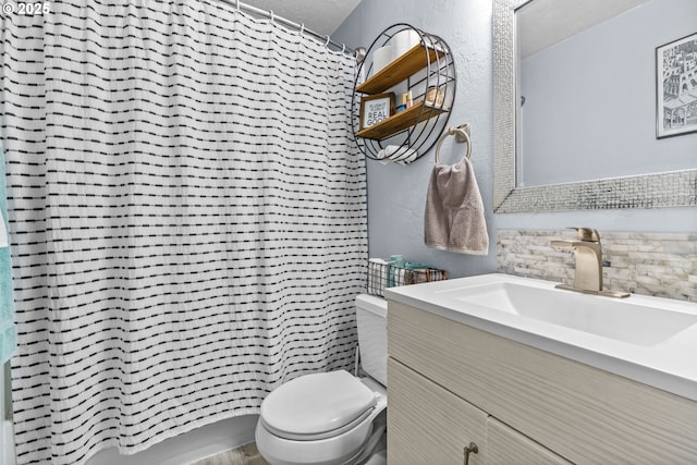 bathroom featuring vanity, tasteful backsplash, and toilet