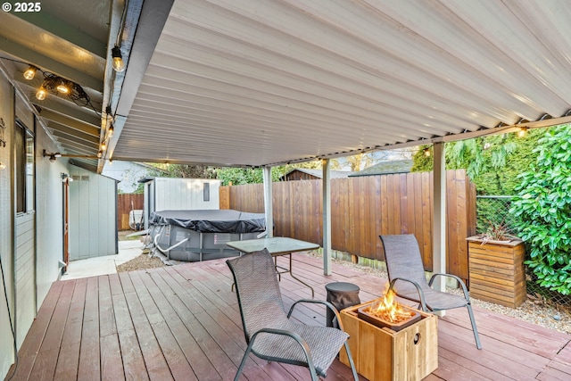 wooden deck featuring a storage unit and an outdoor fire pit