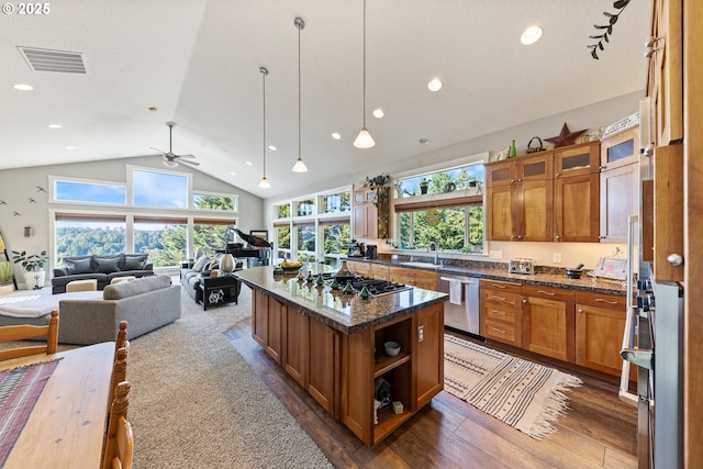 kitchen with ceiling fan, a center island, dark stone counters, and appliances with stainless steel finishes