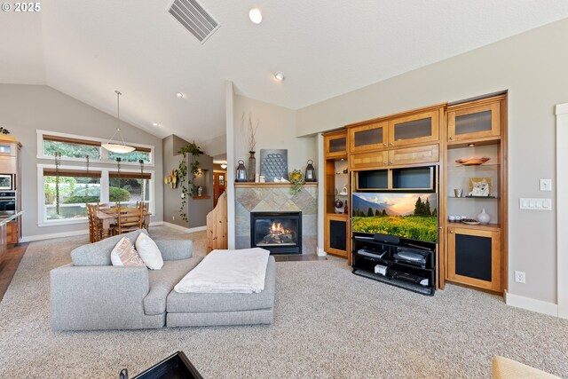 carpeted living room featuring lofted ceiling and a tiled fireplace