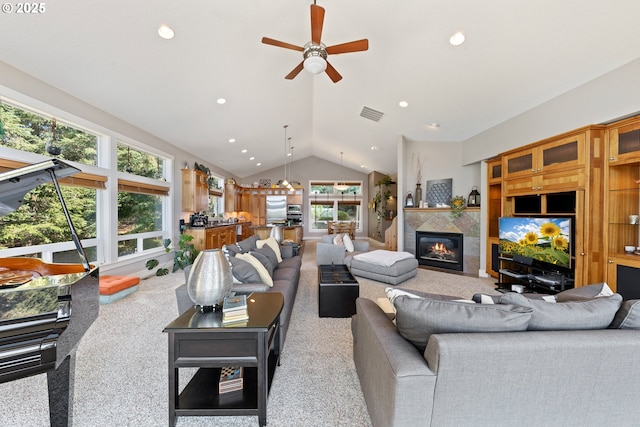 living room with carpet, ceiling fan, lofted ceiling, and a tiled fireplace