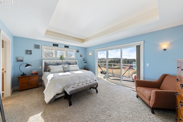 bedroom with access to exterior, light carpet, and a tray ceiling