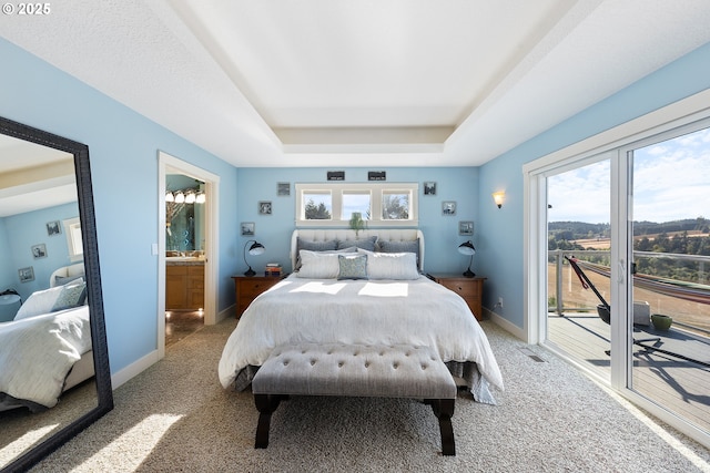 bedroom featuring a raised ceiling, access to exterior, carpet flooring, and ensuite bath