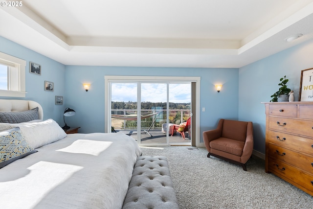 bedroom with carpet, a raised ceiling, and access to outside