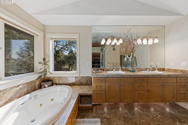 bathroom featuring vanity, lofted ceiling, and tiled tub