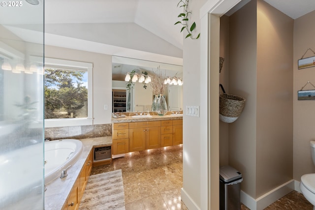 bathroom with tiled tub, vanity, lofted ceiling, and toilet