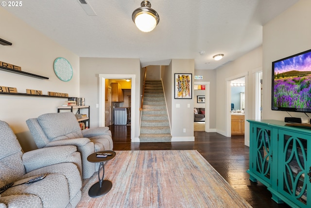 living room featuring a textured ceiling and dark wood-type flooring