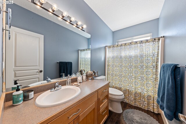 bathroom featuring vanity, vaulted ceiling, hardwood / wood-style flooring, toilet, and a textured ceiling