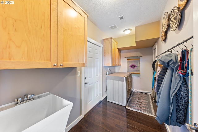 laundry area with cabinets, sink, a textured ceiling, dark hardwood / wood-style flooring, and washing machine and clothes dryer