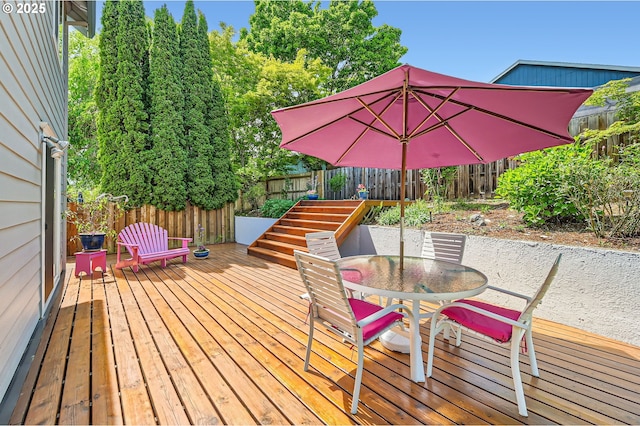 wooden terrace with outdoor dining space and a fenced backyard