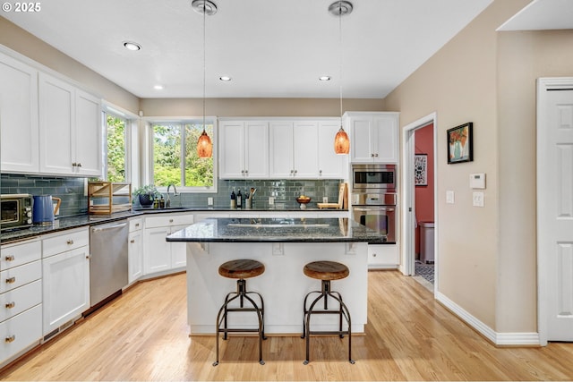 kitchen with stainless steel appliances, white cabinetry, decorative backsplash, a kitchen breakfast bar, and recessed lighting