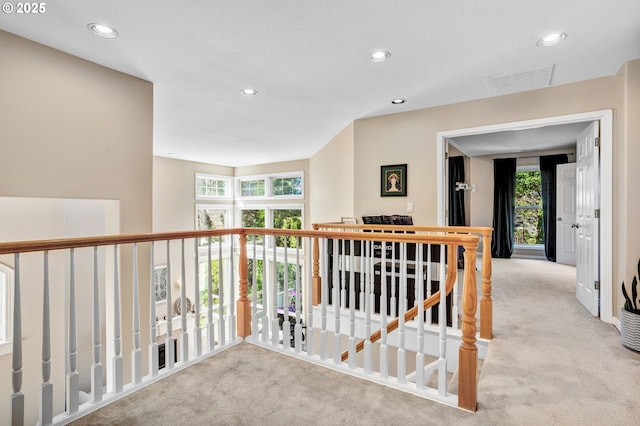 hallway with carpet floors, recessed lighting, and an upstairs landing