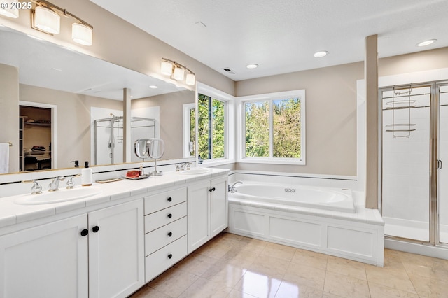 bathroom featuring a stall shower, a bath, double vanity, a spacious closet, and recessed lighting
